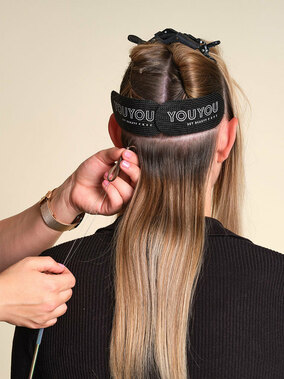 YOUYOU Tressen, Step 2: Haarsträhne mit dem Loop durch den Mikroring ziehen und den Ring zum Haaransatz hochschieben. Er sollte mittig sitzen, sodass links und rechts genug Platz zum Nähen ist. Mit der Zange andrücken. (© YOUYOU Hair)